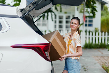 Delivery, unpacking, woman, car trunk, smiling, cardboard box, outdoor, sunny, transportation, logistics, cheerful person, summer outfit, teamwork, convenience, lifestyle, cargo, mobility, ease of use