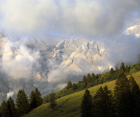Green Hill Slope Against Misty Mountain Peaks