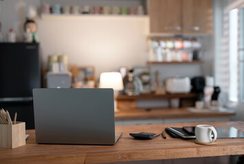 Rear view of simple workspace with laptop on wooden table at home.