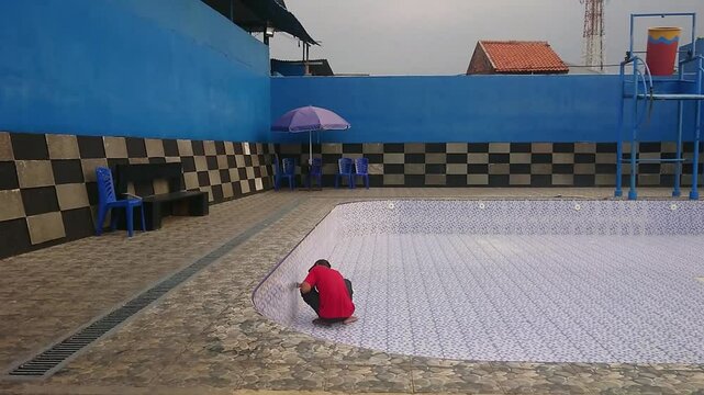 Man Repairing Crack Wall of Swimming Pool 
