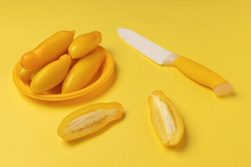 Fresh Yellow Tomatoes and Knife on Vibrant Yellow Background in Modern Minimalist Style