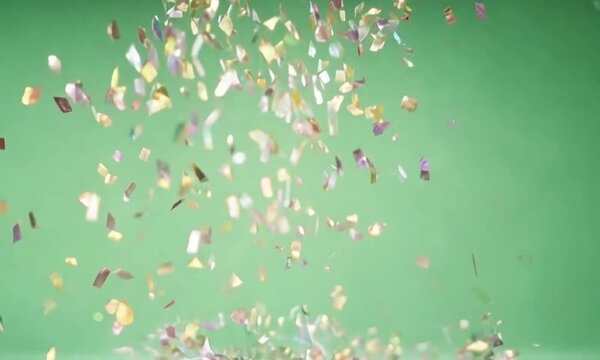 Golden and silver confetti pieces gently drifting down in a spiral pattern, glittering as they move, displayed on a green screen background.