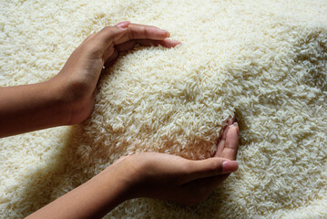A woman's hand scoops Thai jasmine rice into the palm of her hand.
