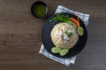 Fried rice with crab, cucumber, spring onion and lime on a black plate