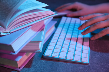 Books with a keyboard on a light blue-pink background.