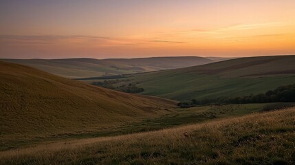 Obraz premium A scenic view of a valley at sunset with rolling hills and a hazy sky.