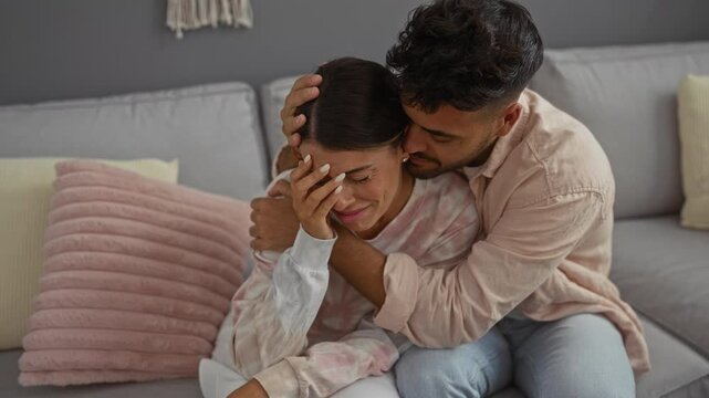 Man comforting crying woman in cozy living room, expressing love and support in an emotional moment at home