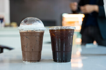 Iced Americano coffee and iced mocha in plastic coffee cup on white table in coffee shop