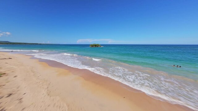 FPV drone shot through palm tree forest and over a beach, toward a rocky isle