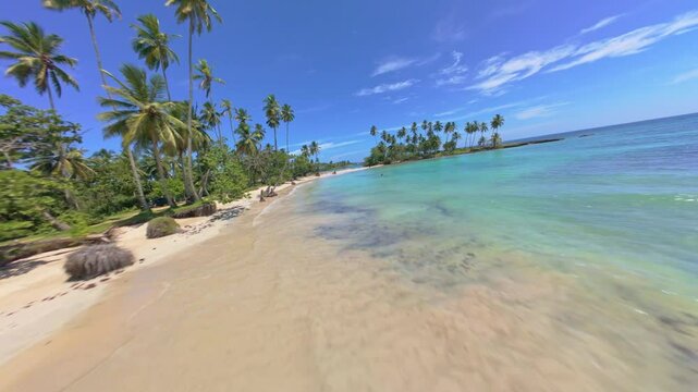 FPV drone shot flying along the Playa los Coquitos beach, in the sunny Caribbean