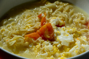 Close-up detail of boiled noodles or yellow noodle soup mixed with egg and tomato, Indonesian handmade food