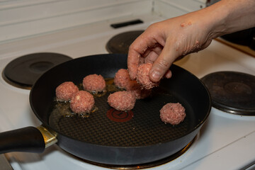 Placing a Meatball into a Frying Pan by Hand