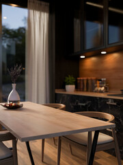 A close-up of a hardwood dining table with armchairs in a contemporary, luxurious black kitchen.