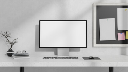 A front view of a computer and decor on a white table against a white wall with a memo board on it.