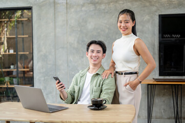 Obraz premium A handsome Asian businessman and an attractive Asian businesswoman are in the office together.