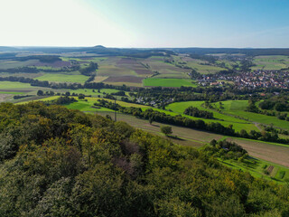 Obraz premium Luftaufnahme, Drohnenfoto der fränkischen Landschaft bei Hammelburg, Bad Kissingen im Sommer mit blauem Himmel, von oben, Vogelperspektive, Thulba, Franken, Bayern, Deutschland 