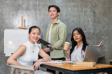 A group of successful Asian startup team members is in a meeting, smiling confidently at the camera.