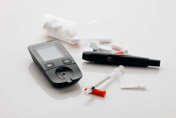 Glucometer, syringe and blood test for diabetes, insulin or sugar balance on white studio background. Medication, needle or pharmaceutical product for healthcare, glucose control and clinic equipment