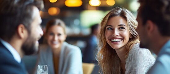 A smiling woman listens intently as she enjoys a conversation with two friends at a cafe.