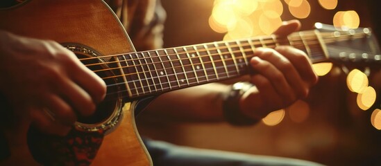 Naklejka premium Close up of a man's hands playing an acoustic guitar with blurred lights in the background.