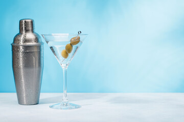 A martini cocktail arranged on a table against a light blue background