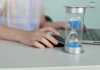 A child using a computer with an hourglass timer