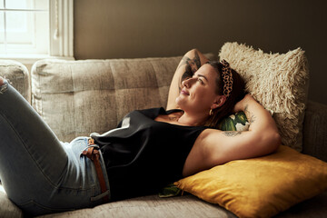 Happy woman, relax and lying with sofa for holiday, weekend or day off in comfort at home. Young,...