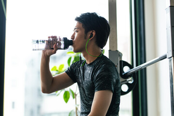 トレーニングジムで水分補給する男性