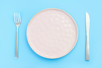 Empty plate on blue background, intermittent fasting concept.