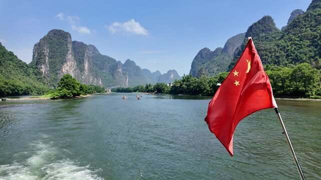 Guilin, China: Point of view of a cruise with the national chinese flag during a sail along the Li river, or Li jiang, between Guilin and Yangshuo lined with steep karst peaks in southern China. 