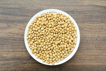 Soybean seeds in a plate on wooden background 