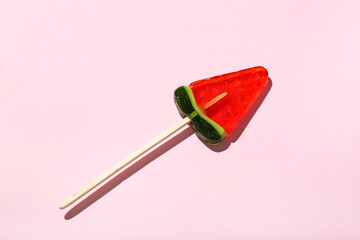 Lollipop in shape of watermelon slice on pink background