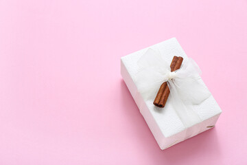 Christmas gift box and cinnamon on pink background