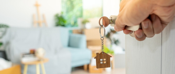 Moving house, relocation. Man hold key house keychain in new apartment. move in new home. Buy or...