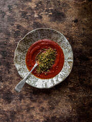 Baked tomatoes cream soup with garlic herbs olive oil bread crumbs on a wooden background, top view
