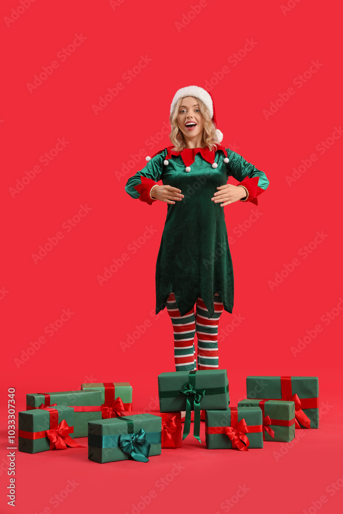 Sticker Funny young woman dressed as elf with Christmas gifts on red background