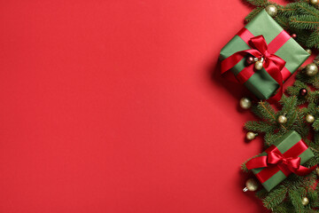 Gift boxes with Christmas tree branches and balls on red background