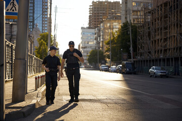 Man woman police officers of patrol team walking city street