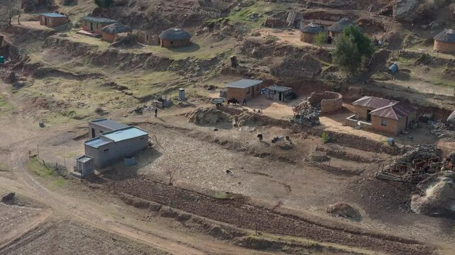 Distant aerial view of cattle drawn cart pulling up hill into rural African village