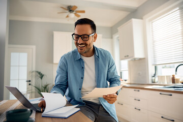 Happy man going through his notes while working at home.