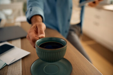 Close up of man having cup of coffee while working at home.