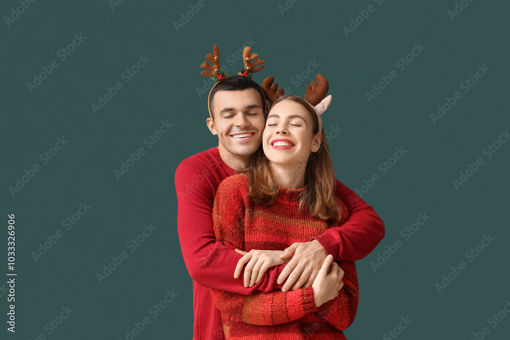 Poster Young couple in reindeer horns on green background