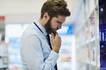 Man, pharmacy and browse shelves for pills, thinking and search for antibiotics at drugstore. Male person, healthcare and aisle for drugs shopping, contemplating treatment and apothecary for choice