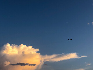 An airplane is flying in the blue sky with huge white clouds.