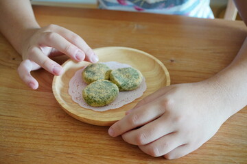 きなこがまぶされた草餅を食べようとしている子供の手。