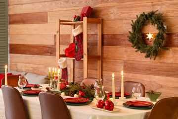 Festive table setting with Christmas decorations and burning candles in dining room