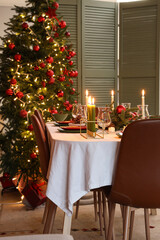 Interior of cozy room with Christmas tree, decorations and served dining table