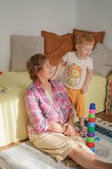 boy with red hair, grandson and grandmother playing together
