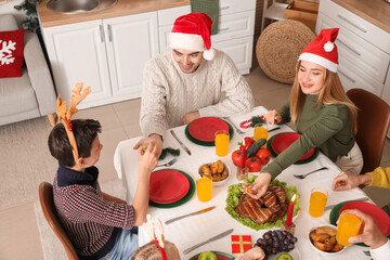 Happy family in Santa hats having dinner at home on Christmas eve