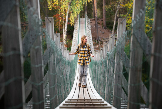 woman in yellow shirt crossing a suspension bridge in Finland